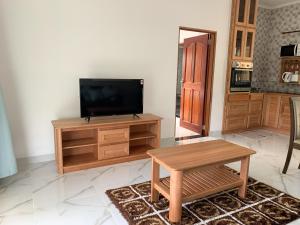 a living room with a television on a wooden entertainment center at CAM Getaway Villa in Praslin