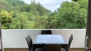 a table and chairs on a balcony with a view of trees at CAM Getaway Villa in Praslin