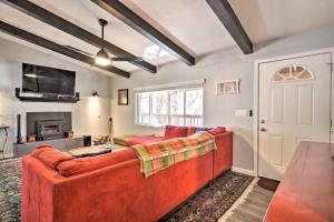 a living room with a red couch and a fireplace at Show Low White Mountain Cottage with Deck! in Show Low
