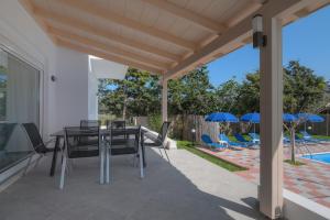 un patio con mesa, sillas y piscina en Romantic Evas Cottage, en Gouves