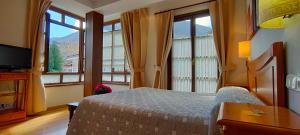 um quarto com uma cama, uma televisão e janelas em Hotel Rural la Plaza em Caso
