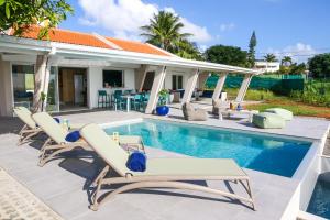 una piscina con tumbonas y una casa en Villa 5* avec piscine et vue mer exceptionnelle, en Fort-de-France