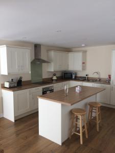 cocina con armarios blancos y encimera de madera en Hilltop Cottage en Dursley