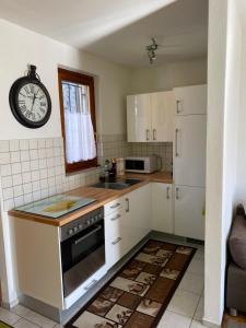 una cocina con armarios blancos y un reloj en la pared en CASA PONTE: Gordola, en Gordola