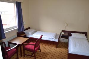 バレストランドにあるMidtnes Hotelのベッド2台、テーブルと椅子が備わるホテルルームです。