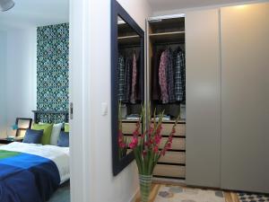 a bedroom with a closet with a bed and a vase of flowers at Apartament Metro Kowieńska in Warsaw
