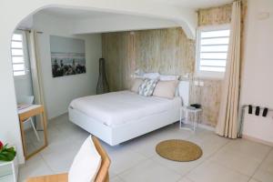 Un dormitorio con una cama blanca y dos ventanas. en Villa 5* avec piscine et vue mer exceptionnelle, en Fort-de-France 26 fotos más