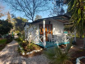 Casa blanca pequeña con porche y mesa en Bellerofon Beach Otel, en Cıralı