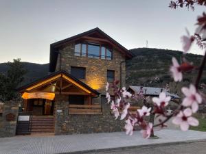 a large brick house with a mountain in the background at Can Congost in Sort