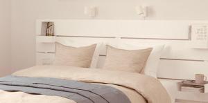 a bedroom with a bed with white walls and pillows at Charme House Palau in Palau
