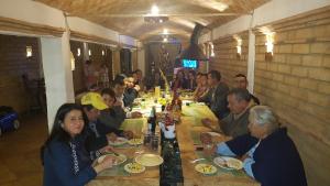 een groep mensen die aan een lange tafel zitten bij Casona Real Santa Barbara in Ráquira