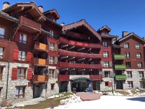 un gran edificio con balcones rojos. en Spacious ski-in ski-out apartment 4-6 pax, 161 Sources de Marie Arc 1950, en Arc 1950
