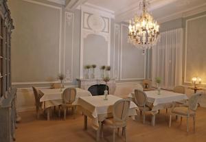 una sala da pranzo con tavoli, sedie e lampadario a braccio di Guesthouse Mirabel a Bruges