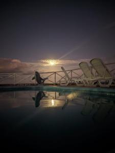 a group of chairs sitting next to a pool at night at Pousada Portal dos Coqueirais in Jequia da Praia