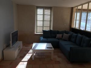 a living room with a blue couch and a tv at Les portes du marais in Benet