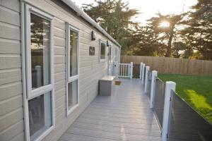 une terrasse couverte en bois avec un banc sur une maison dans l'établissement 6 berth luxury lodge in Christchurch Dorset, à Christchurch