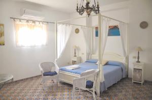 a bedroom with a canopy bed and two chairs at Le Mànnare Case Vacanze di Metopa srl in Piano Conte