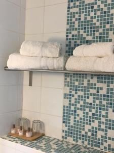 a bathroom with towels on a shelf and blue tiles at Le Cannier Hotel in La Seyne-sur-Mer