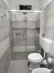 a bathroom with a toilet and a glass shower at appartamento dei colori anticaglie in Punta Secca