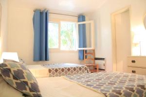 a bedroom with two beds and a window with blue curtains at Fantástica Casa com 4 Quartos na Praínha in Alvor +33 photos