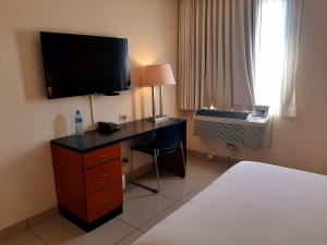 a bedroom with a desk with a television on a wall at Comfort Inn Real San Miguel in San Miguel