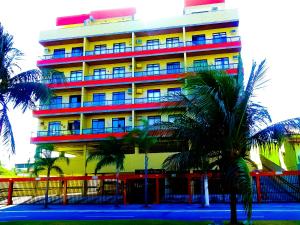 un edificio colorido con palmeras delante en Cobertura Climatizada, Spa no litoral, en Cabo Frío