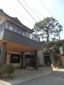 une maison avec un balcon et un arbre en face de celle-ci dans l'établissement Minshuku Ginmatsu, à Kanazawa