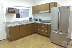 eine Küche mit Holzschränken und einem Kühlschrank aus Edelstahl in der Unterkunft Departamento Topacio 3 Joyas del Mar San Carlos in San Carlos