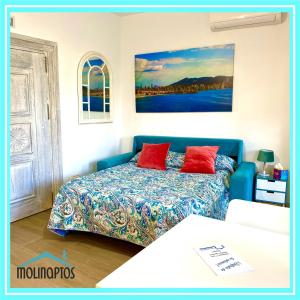 um quarto com um sofá e uma cama com almofadas vermelhas em Loft frente al Puerto by Molinaptos em Benidorm