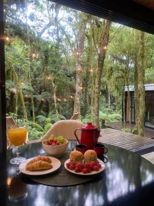 a table with two plates of food and a drink at Chalé dos Alpes in São Francisco de Paula