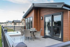 a house with a deck with a table and chairs at Lilac Lodge with Hot Tub in York