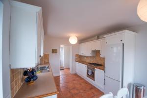 a kitchen with white cabinets and a tile floor at Beautiful coastal house at the Drowes Rivermouth in Bundoran +34 photos