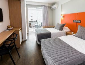 Una habitación de hotel con dos camas y un escritorio. en Tropikalya Gold Hotel, en Balneário Camboriú 89 fotos más