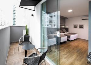 um quarto com uma varanda com uma cama, uma mesa e cadeiras em Tropikalya Gold Hotel em Balneário Camboriú