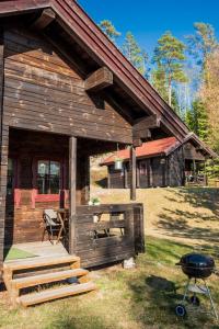 una cabaña de madera con una parrilla frente a ella en Noretjärns Stugby, en Årjäng