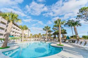 a swimming pool with palm trees and chairs at a resort at Direct Oceanfront Villa - Heated Pool & Breathtaking Ocean View in Hilton Head Island