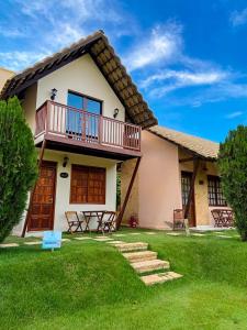 a house with a balcony and a grass yard at Hotel Chale Lagoa Dos Ingas in Martins