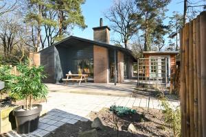 a small house with a glass extension in a garden at ZEN-bungalow NO 1 met sauna en hottub in Rheezerveen