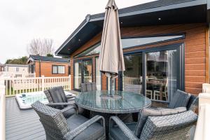 a patio with a glass table and chairs and an umbrella at The Crucible lodge with Hot Tub in York