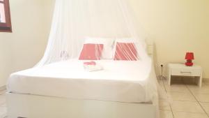sypialnia z białym łóżkiem z 2 poduszkami w obiekcie Maison de 3 chambres avec jardin clos et wifi a Deshaies a 1 km de la plage w mieście Deshaies