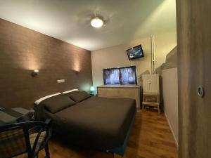 a small bedroom with a bed and a television at Hotel Les Arcades - La-Roche-en-Ardenne in La Roche-en-Ardenne