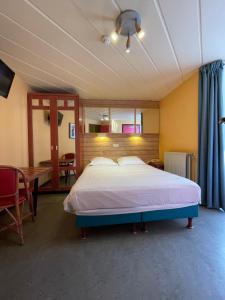 a bedroom with a large bed and a table at Hotel Les Arcades - La-Roche-en-Ardenne in La Roche-en-Ardenne
