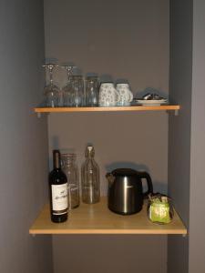 a shelf with a bottle of wine and a pot and glasses at Bosrand81 in Hechtel
