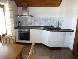 uma cozinha com armários brancos, um lavatório e uma mesa em Eifel Panoramablick em Kelberg