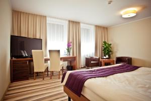 a hotel room with a bed and a desk and a television at Hotel Mazovia Airport Modlin in Nowy Dwór Mazowiecki