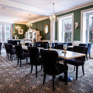 a dining room with tables and chairs and windows at Lansdowne House with Private Car Park in Llandudno