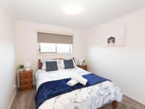 Schlafzimmer mit einem Bett mit blauer und weißer Bettwäsche in der Unterkunft Jindalee 3 34 Twynam St in Jindabyne