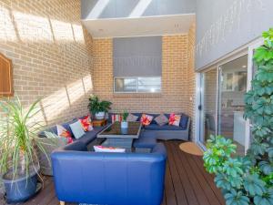un patio con sofás azules y una mesa en Jindalee 3 34 Twynam St, en Jindabyne