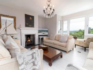 a living room with white furniture and a fireplace at Swn Y Wylan in Menai Bridge
