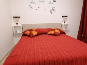 a bed with a red comforter and two pillows at LUX IUN Q2026 in Lanusei